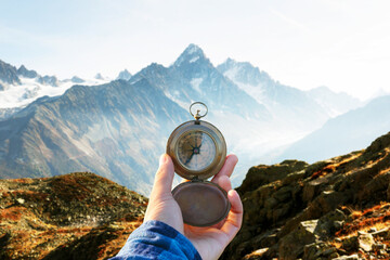 Monte Bianco mountains range and tourist hand with old metal compass on a foreground. Vallon de Berard Nature Preserve, Chamonix, Graian Alps. Travel concept. Landscape photography
