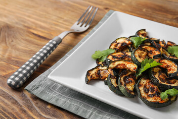 Plate with tasty grilled zucchini on wooden background, closeup