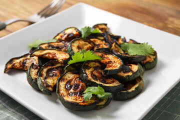 Plate with tasty grilled zucchini on table, closeup