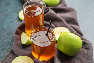 Glasses of apple juice and fresh fruits on dark background
