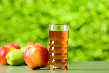 Glass of apple juice and fresh fruits on table outdoors