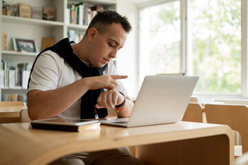 The student studies online lessons on the institute's website. A smart man to study at the institute. Reads an e-book in the university library. Surf the Internet in between classes.