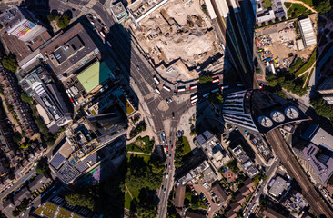 Birds eye view of tall financial and commercial buildings with shadow and cars moving on city street during a bright sunny day in London city