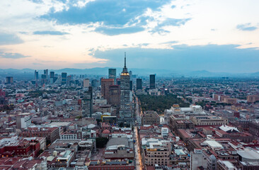 Aerial view of financial skyscrapers and residential buildings with moving vehicle on street during day in Mexico City under cloudy blue sky