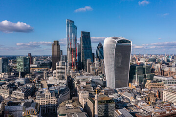 Aerial view of financial tower surrounded by small buildings in the beautiful city of London on a cloudy day with blue sky