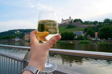 a glass of German crisp semi-dry white wine with Marienberg Fortress and the vineyards in the...
