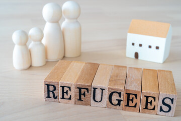 難民｜「REFUGEES」と書かれた木のスタンプと人形、家のおもちゃ