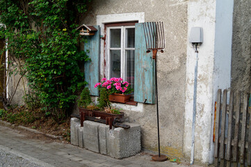 Fototapeta na wymiar a Bavarian countryside scenery with an old house, pink geraniums on the windowsill and an old tall rake leant against the wall (Bavaria, Germany)