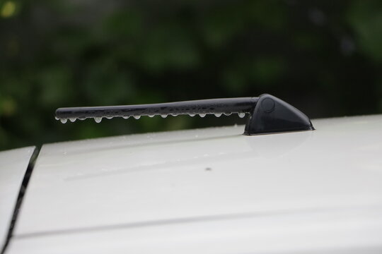 Close up picture of a car's antenna, on a rainy day.