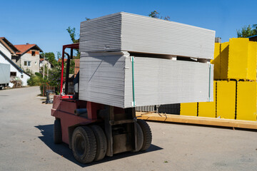 Close up on fork lifter carry the pile of drywall gypsum boards on the palett