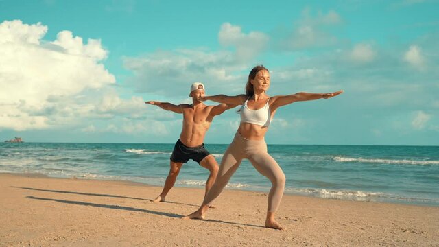 Couple training - Young sports couple doing acro yoga exercises on sand beach. Couple making yoga exercises on sand. fitness, sport, people and lifestyle concept, Caucasian fitness model.