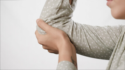 Elbow pain. Female hand touches elbow on white background. Close-up