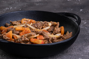 Sliced and fried filet mignon with tomato and onion in an iron skillet