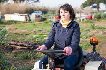 Positive woman working on small farm tractor. High quality photo