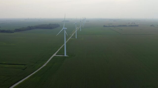 Aerial view of wind turbines on green rural field, fogy weather