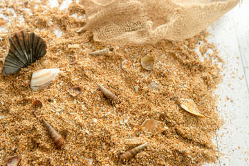 Sand and seashells on white wooden background