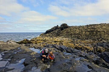 A mother and daughter exploring the tidal pools off of North Beach, in Naikoon Provincial Park, Haida Gwaii, British Columbia, Canada