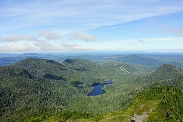 A forested valley with a beautiful blue lake in the middle, with the ocean in the background, on the west side of Graham island in the Queen Charlotte mountains, Haida Gwaii, British Coumbia, Canada