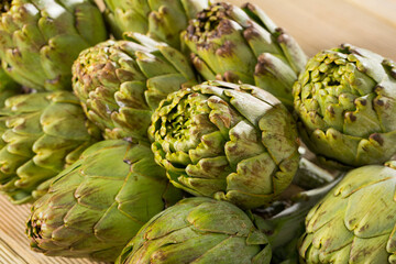 Fresh ripe green artichokes on light wooden background