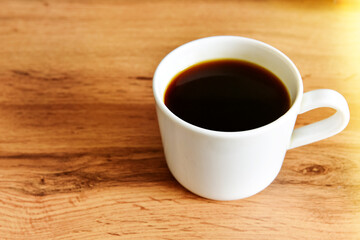 White cup of strong black coffee on wooden surface close up
