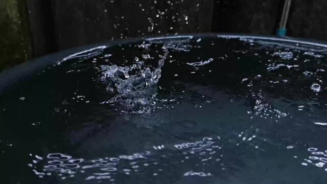 Footage, close-up, raindrops on a black enamelware. in the rainy season of Thailand.