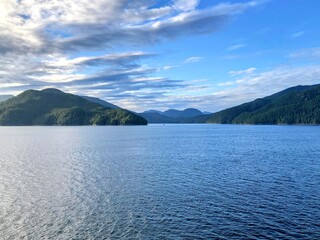 Naklejka na ściany i meble Majestic views of the forested mountains and beautiful blue ocean along the british columbia coast along the BC ferries inside passage route, on a beautiful sunny day