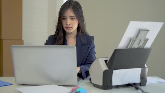Asian women are using document scanners to transfer data to the laptop.