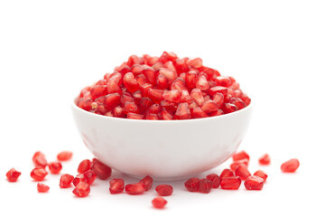 Close-up of One organic red pomegranate (Punica granatum) and red pods(seed) in a white ceramic bowl isolated over white background.