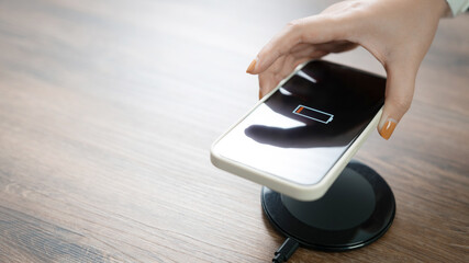 Woman hands plugging a charger in a smart phone. Charging Smartphone with Wireless Charging Pad at Home.