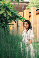 Beautiful Asian Woman posing in  tropical garden with evening sunlight