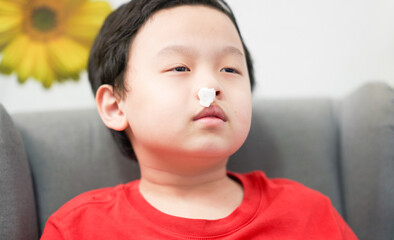 asian little boy nosebleed with gauze pack to stop epistaxis