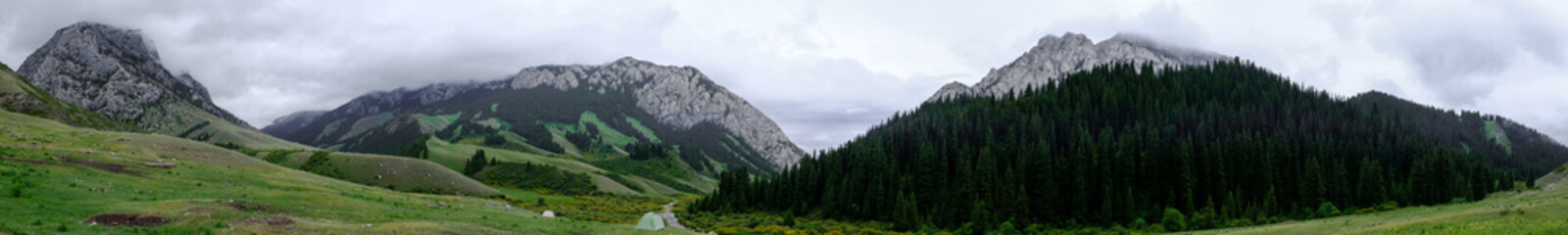 Tent with rocky mountains and cloudy sky on. background. Nature background. Wilderness background. Adventure travel concept. Komirshi gorge in Kazakhstan.