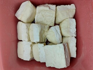 Concept photo of white tofu on a red background. Good for health because it contains a lot of protein.