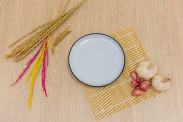 A round white plate was placed on the table, and garlic, onion, rice were placed around it. - Powered by Adobe