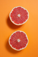 cut red grapefruit on orange background