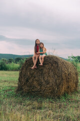 Naklejka na ściany i meble two little sisters sit on a haystack. High quality photo