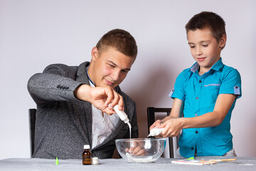 Chemistry education and training concept. Close-up of a boy and his dad doing a home chemical...