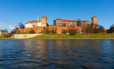 Naklejka na ściany i meble Medieval fortified architectural complex of Wawel Castle and bell tower of Archcathedral Basilica on banks of Vistula river in springtime, Krakow, Poland.