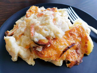 Baked mixed vegetables in cheese sauce with a fork on a blue plate.