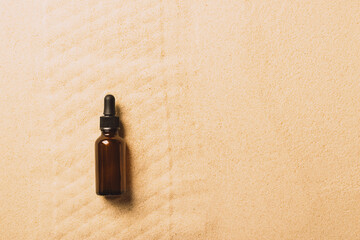 Bottle of serum oil cosmetic product beach sand background. Abstract podium product presentation on...