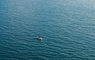 Small fishing boat in the middle of the blue sea.