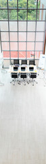 Top view shot of conference meeting room table in empty company office full of laptop computers coffee cups report data paperwork documents black chairs and glass board near building glass windows