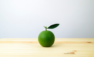 Sweet orange fruit on a wooden board against the white background side view, orange with the green leaf isolated. Copy space for text.