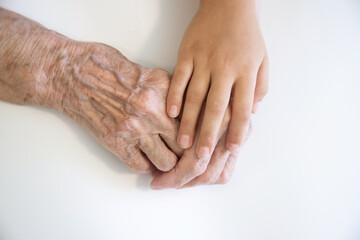 Fototapeta premium The hands of the child in the hands of the grandmother, the old brownish skin in the elderly woman, motherly love and care.