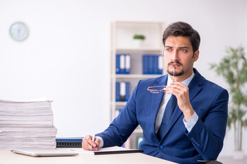Naklejka premium Young male employee and too much work in the office