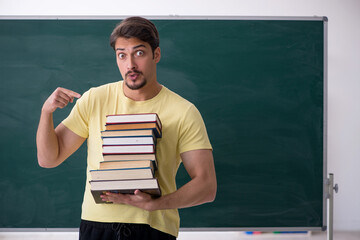 Young male student holding many books