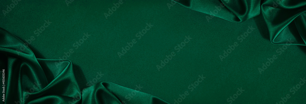 Wall mural dark green silk satin background. beautiful soft folds on the smooth surface of the fabric. luxury b
