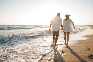 Young beautiful couple walking on beach near sea