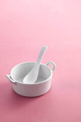 Ceramic spoon in cup on pastel background
