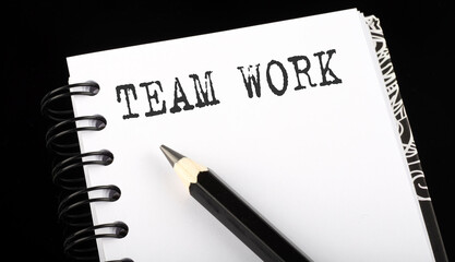 TEAM WORK written text in small notebook on a black background